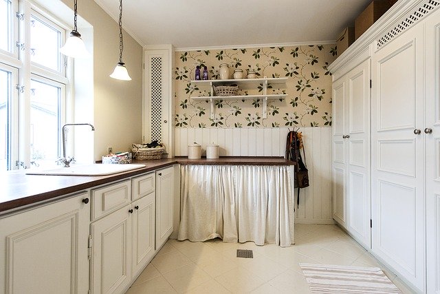 Picture of a white kitchen. On the left side of the photo you see kitchen cabinets and the windows. On the right side there are kitchen closets. 